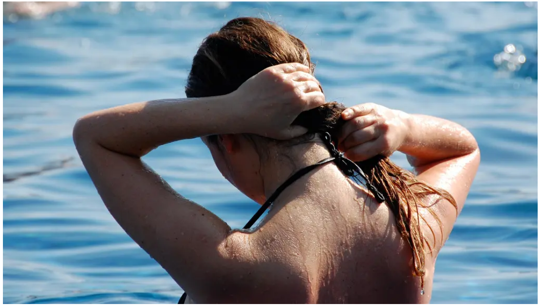 Summer damaged hair after sun and salt water, woman at the beach showing dry wavy hair needing repair and hydration