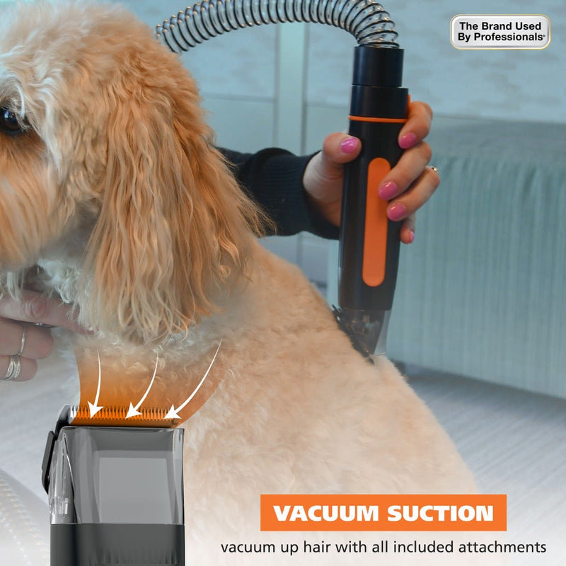 A pet grooming vacuum attachment being used on a light tan dog. A person's hands with pink nail polish hold the black and orange handheld unit, with suction arrows and text overlays highlighting vacuum pickup.