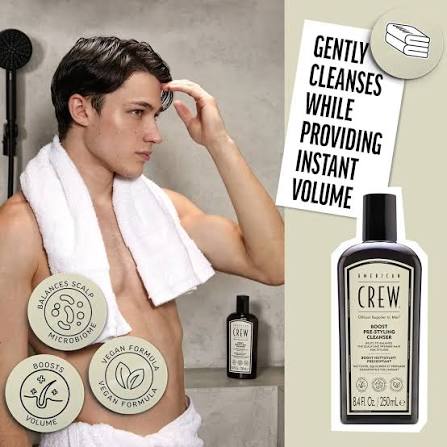 Man with a towel around his neck looking at his hair, with American Crew product packaging and text on a gray background.
