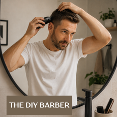 A man in a white t-shirt uses an electric clipper to shave his head and face, viewed from behind inside a mirror. A text overlay at the bottom reads 'THE DIY BARBER'.