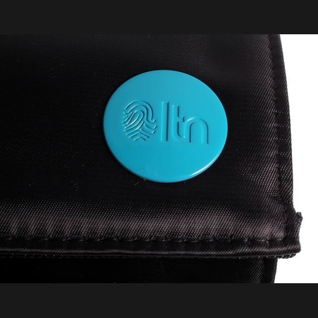 Close-up of black LTN roll mat bag with turquoise circular logo badge on the flap