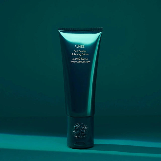 Oribe Curl Control Silkening Creme tube on a teal background