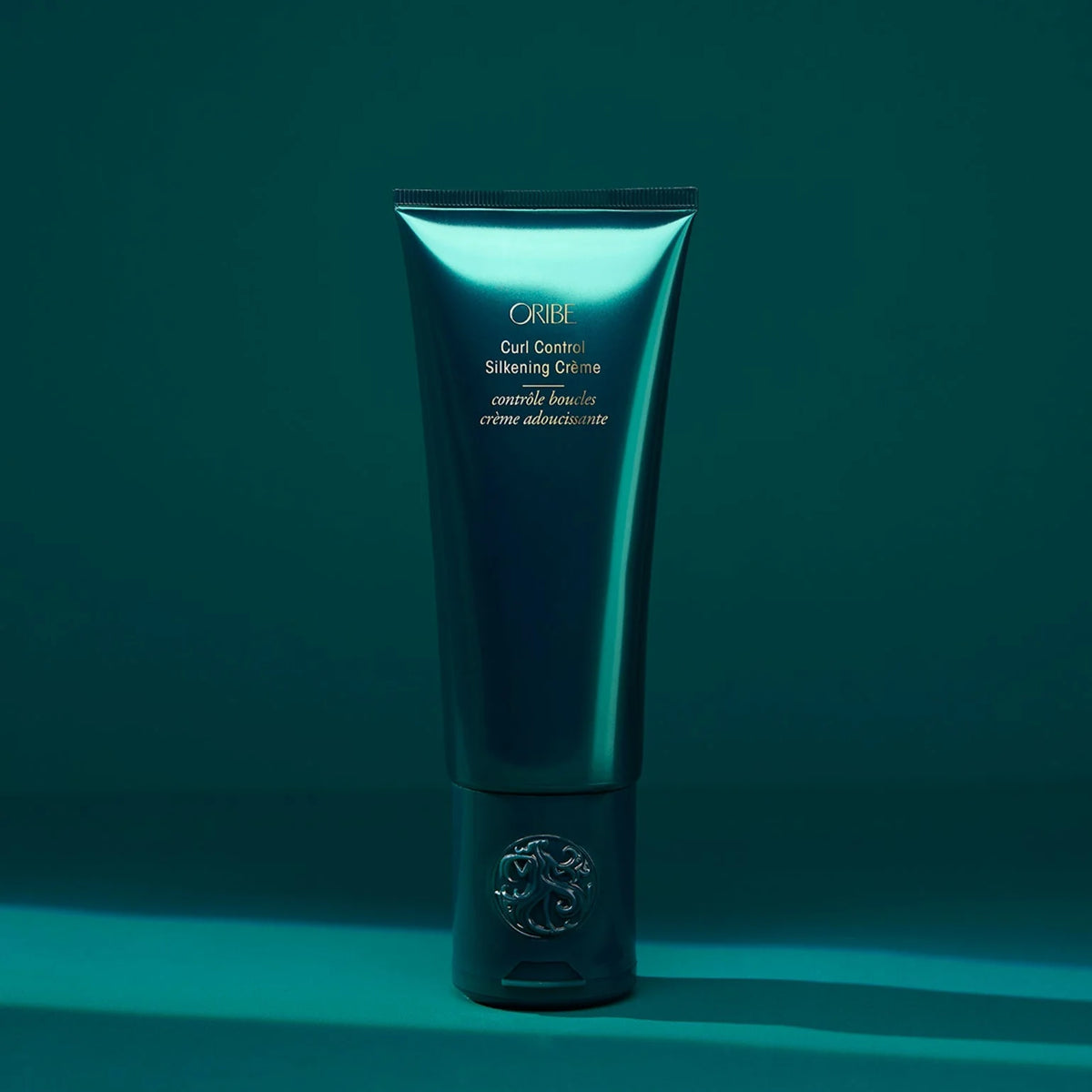 Oribe Curl Control Silkening Creme tube on a teal background