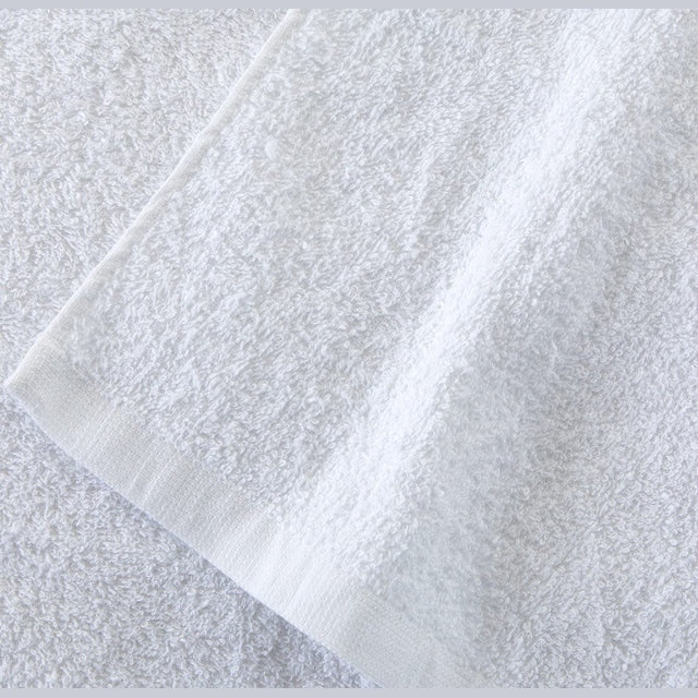 Close-up of white cotton washcloth showing soft terry texture and hemmed edge