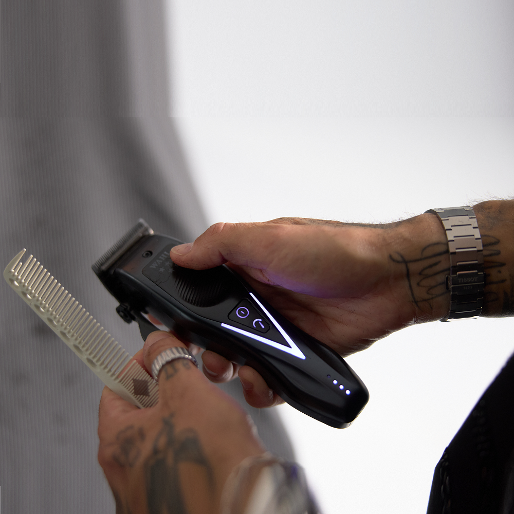 Barber holding Wahl Vapor Switch clipper and comb while preparing to cut hair