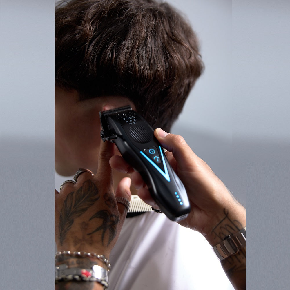 Barber using Wahl Vapor Switch cordless clipper to trim hair around client’s ear