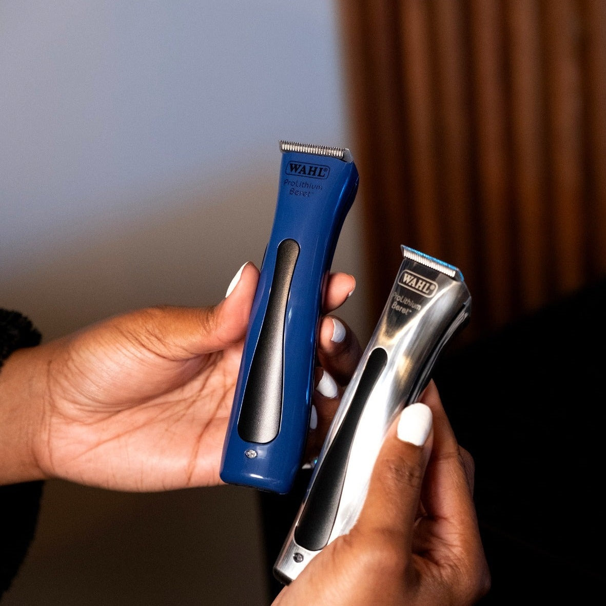 Person holding blue Wahl Beret trimmer next to a silver Beret trimmer for comparison