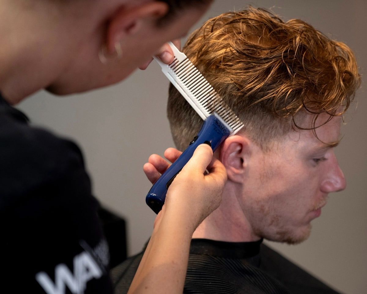 Barber using blue Wahl Beret cordless trimmer to shape a client’s short haircut