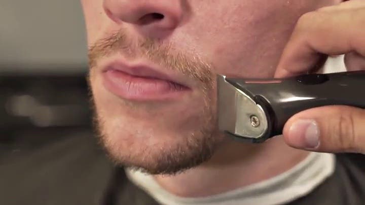 Cordless trimmer detailing a man’s moustache and beard line at the cheek